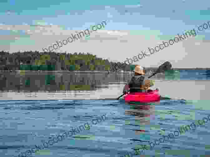 A Lone Kayaker Paddles Through Calm Waters, Exploring A Scenic Coastline. The Complete Sea Kayakers Handbook Second Edition